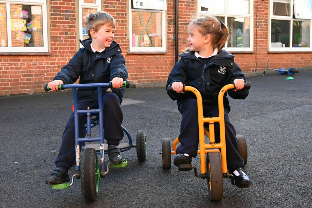 Reception and Year 1 pupils playing on scooters